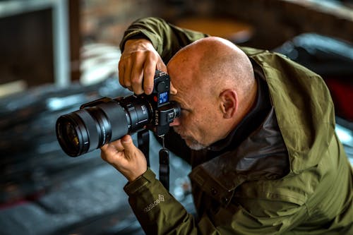 Man in Green Jacket Taking Photo Using Black Dslr Camera