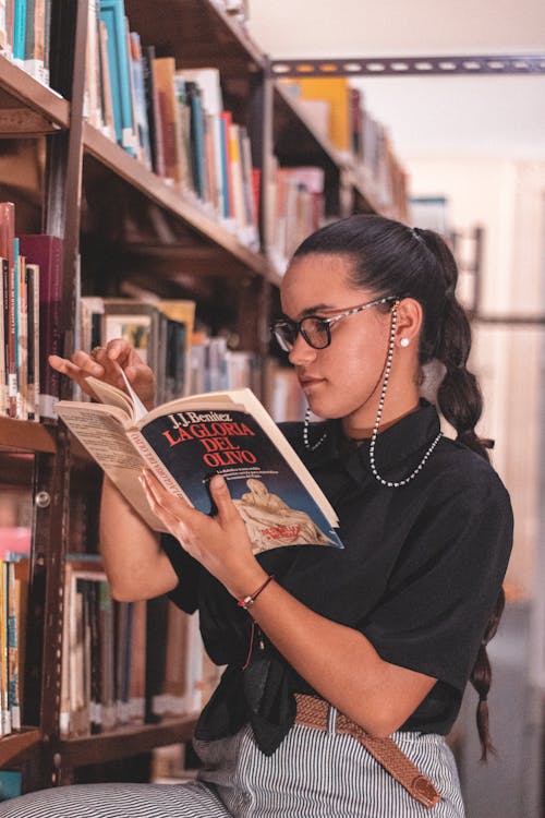 Free Woman Reading a Book in the Library Stock Photo