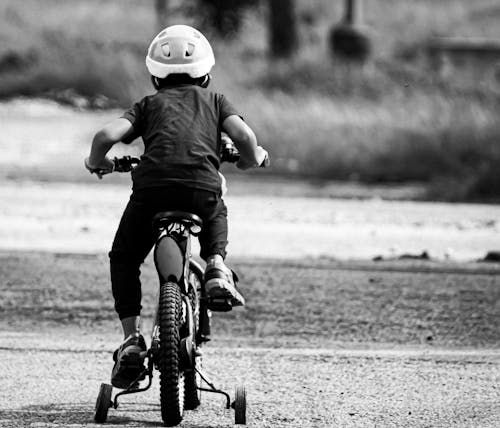 Free Grayscale Photo of Kid Riding Bicycle Stock Photo