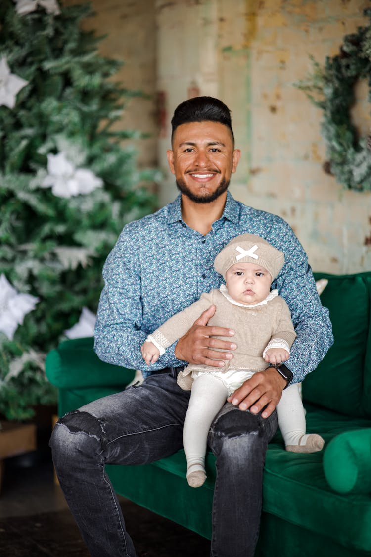 Man Sitting On Sofa And Holding Baby Girl