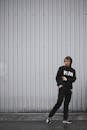一个穿着黑色运动服的人正对着户外的灰色墙壁摆姿势，准备行动