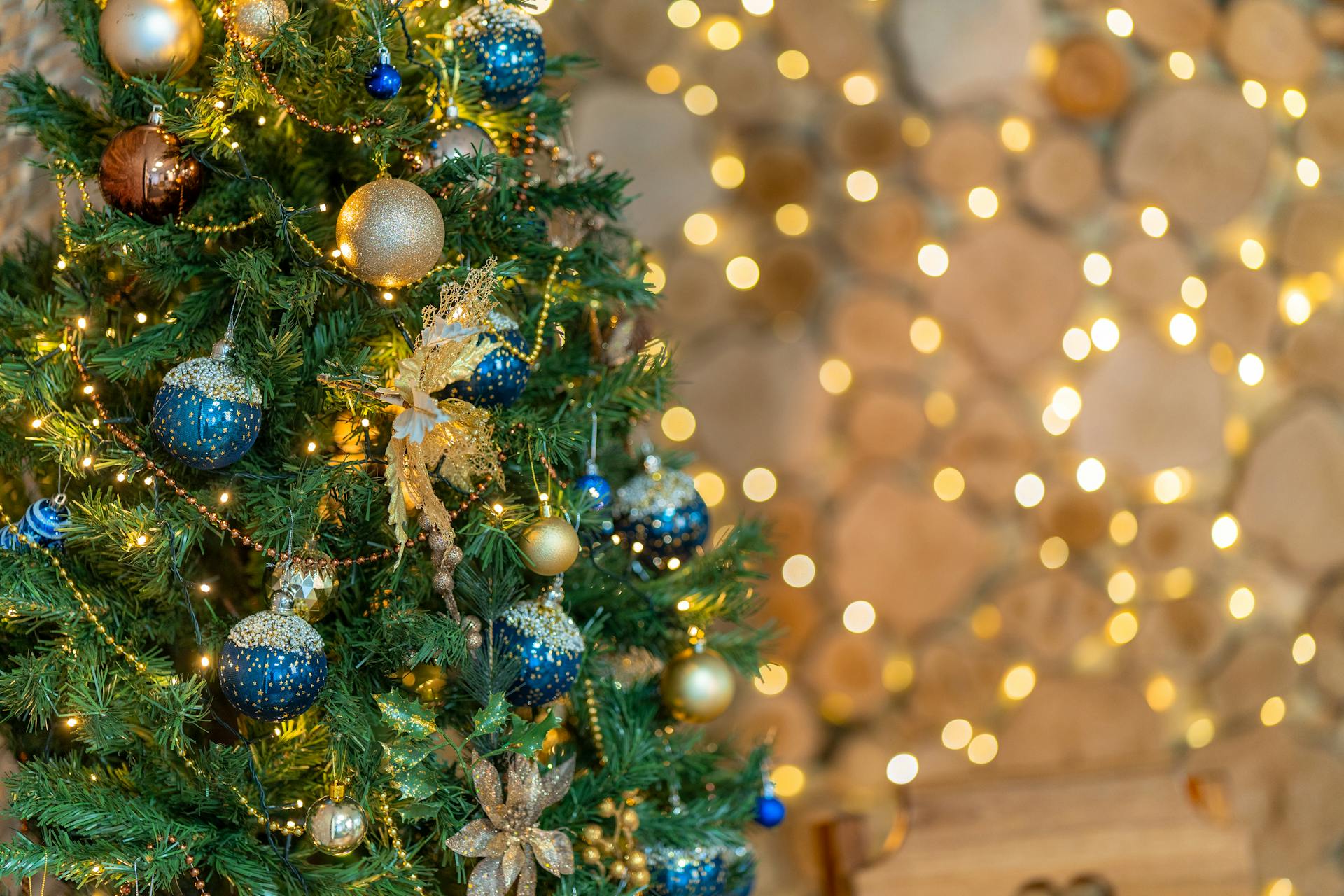 A beautifully decorated Christmas tree with gold and blue ornaments in a cozy indoor setting.