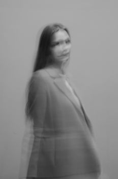 Artistic blurred monochrome portrait of a woman wearing a suit jacket, conveying a dreamlike mood.