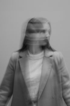 A grayscale, defocused portrait capturing motion blur of a woman in a suit jacket.