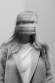 A monochrome image capturing the artistic motion blur of a woman in a suit jacket.
