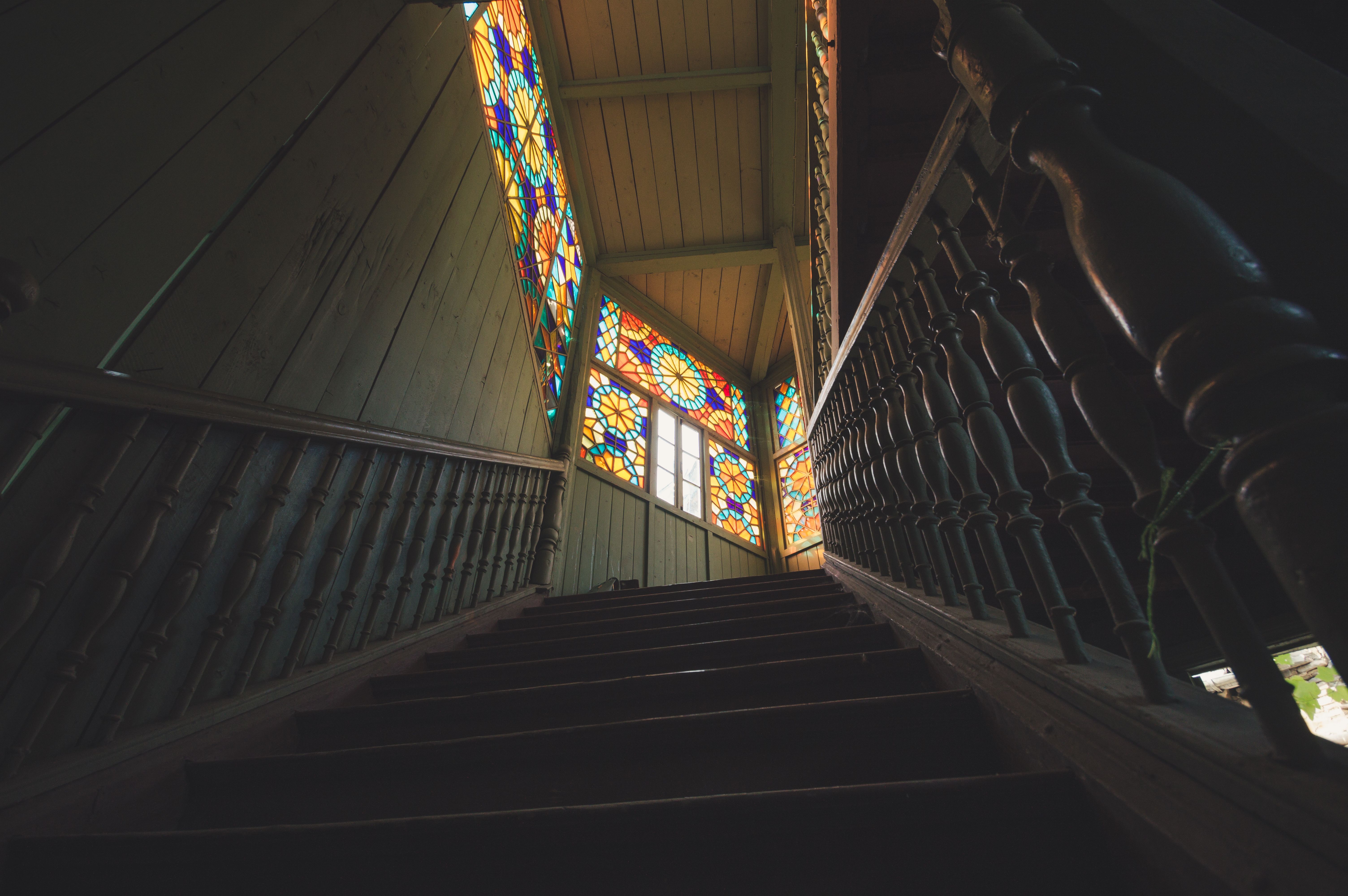 A vintage wooden staircase leading to stained glass windows