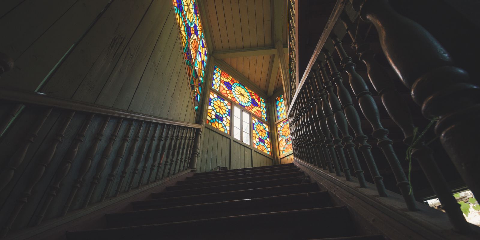 A vintage wooden staircase leading to stained glass windows