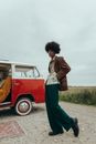 Woman in Brown and White Plaid Dress Shirt and Black Pants Standing Beside Red Car during
