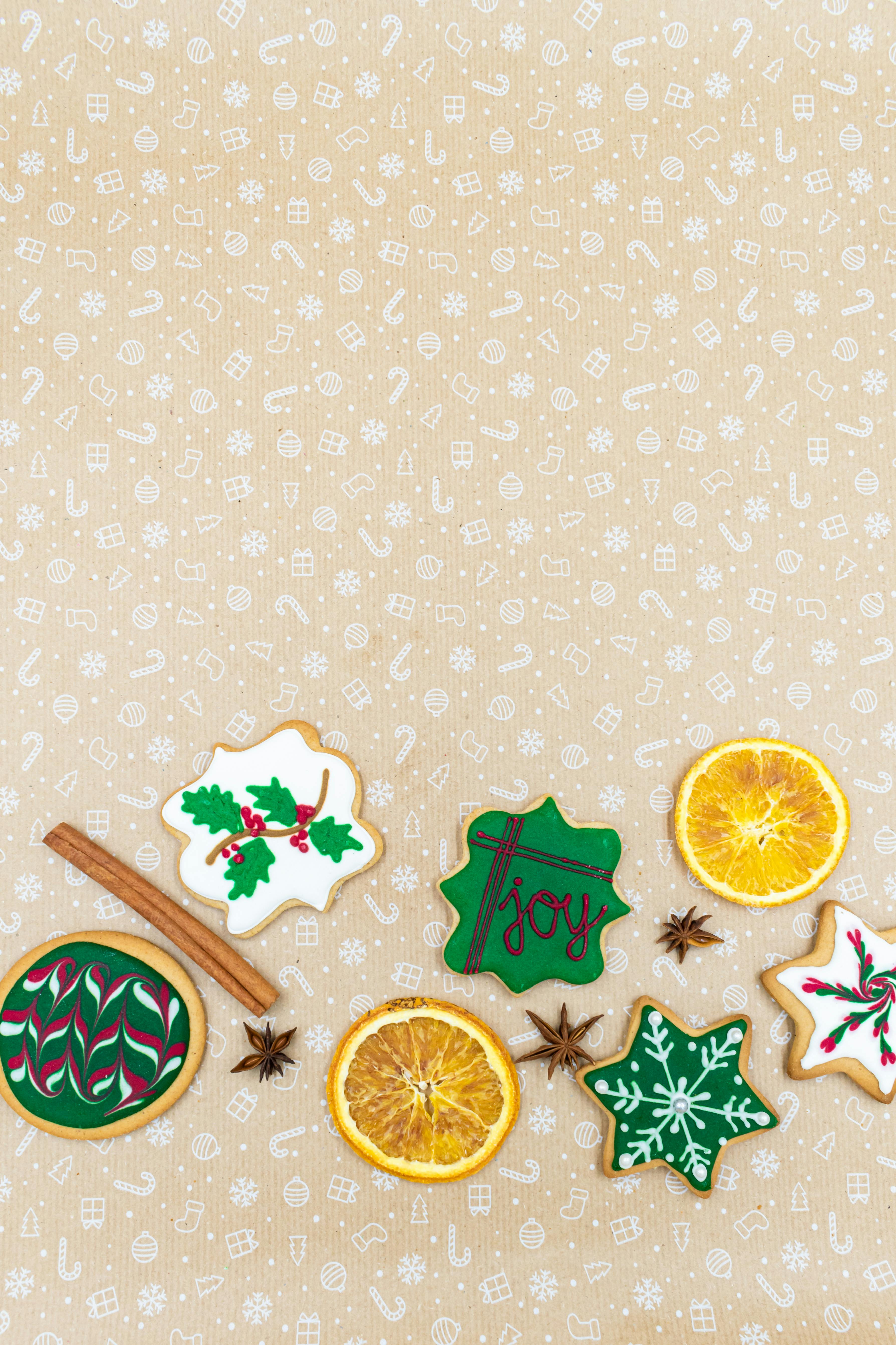 Overhead view of Christmas cookies, orange slices, and spices on a festive background.