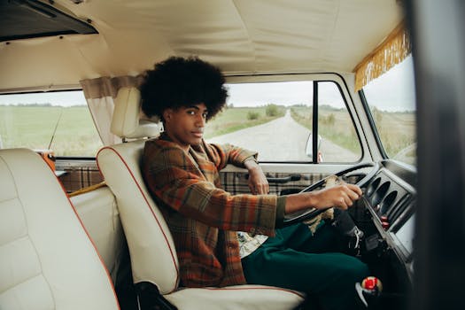 A young man with an afro enjoying a scenic road trip in a retro van, exuding vintage style and wanderlust.