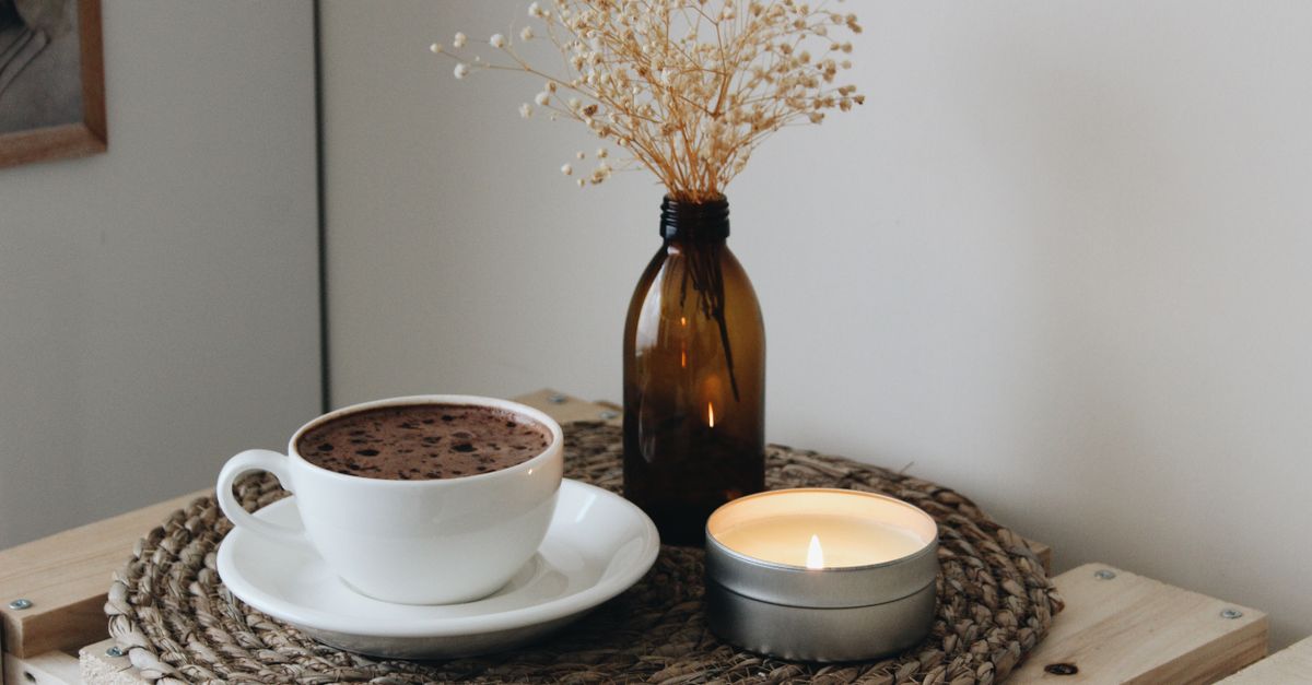 Warm and inviting hygge scene featuring a cup of hot chocolate and a candle on a woven mat. - Evidence evidence guide for cacao mood randomized trial