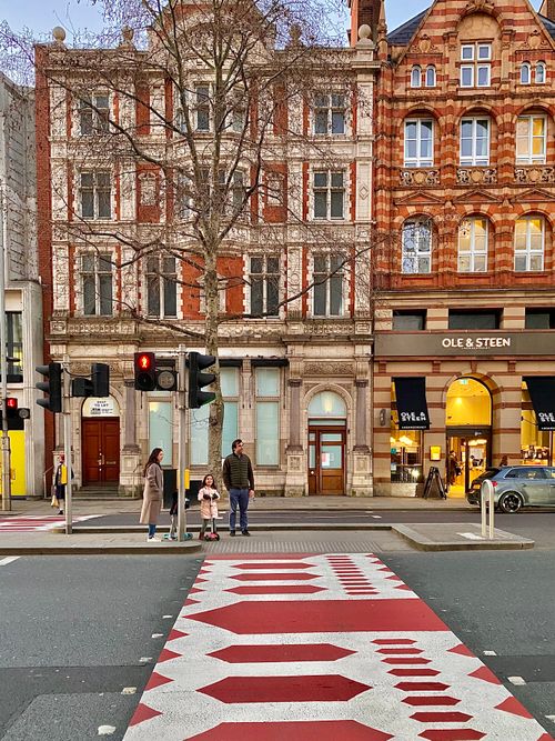 Free Family waiting at a crosswalk in London's picturesque street with historical architecture. Stock Photo