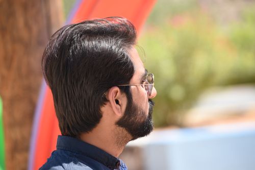 Free A profile view of a man with sunglasses in a park setting, capturing leisure and relaxation in Dubai. Stock Photo