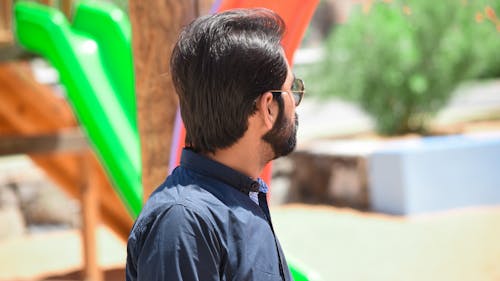 免费 身穿黑色纽扣衬衫的男人站在绿色和棕色的幻灯片附近 素材图片