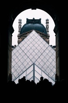 Silhouette view of the Louvre Pyramid with historic architecture in Paris.