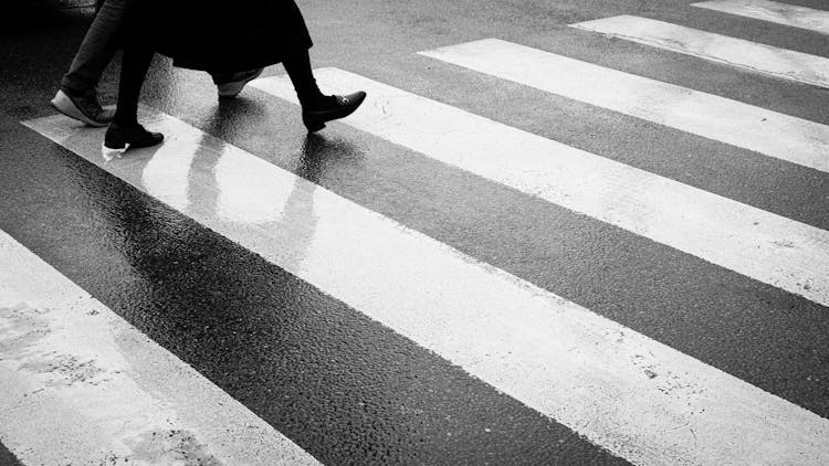 Legs Of People Walking On Zebra Crossing In Black And White