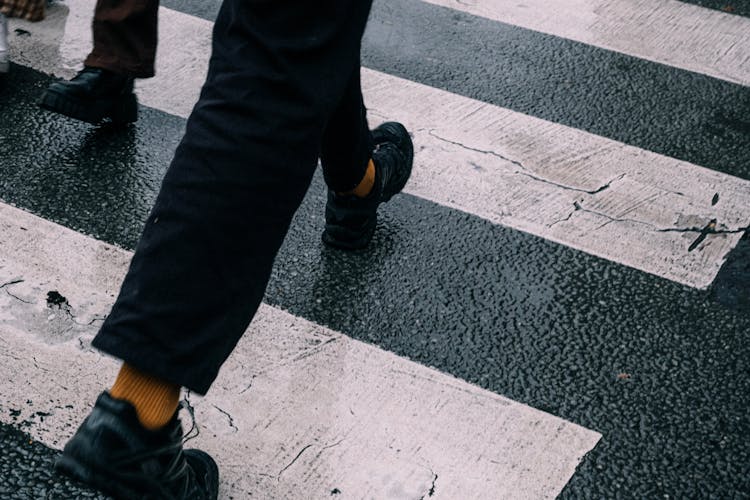 Close-up Of Man Legs Walking On Crosswalk