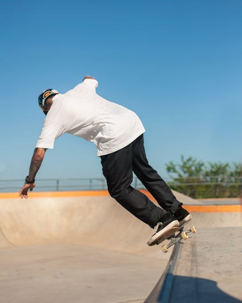 A Man in White Shirt and Black Pants Skating at the Park