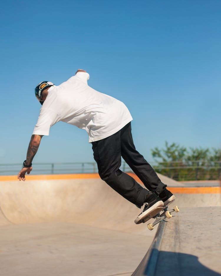 A Man In White Shirt And Black Pants Skating At The Park