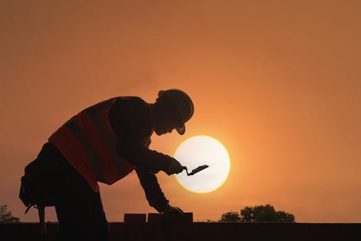 A construction worker's silhouette against a vibrant sunset sky, symbolizing hard work and dedication.