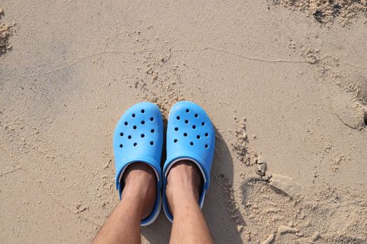 Person Wearing Blue Rubber Clogs Standing on Sand