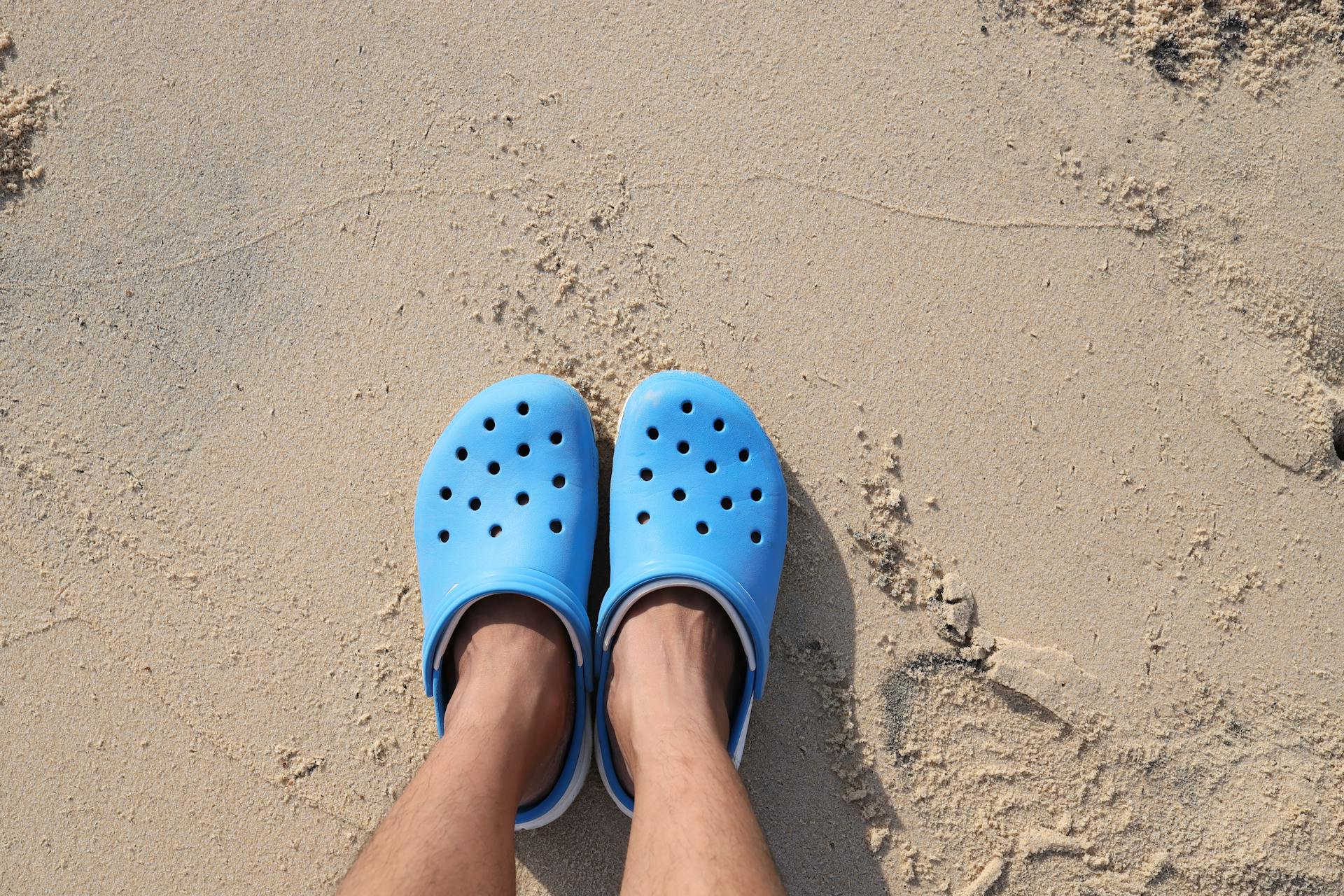 Person Wearing Blue Rubber Clogs Standing on Sand
