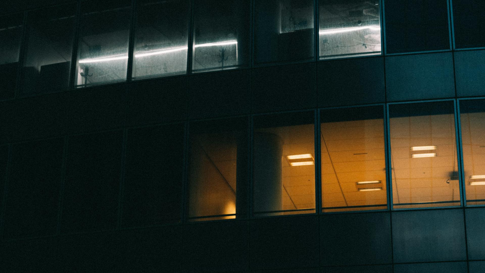 Dark exterior of an office building illuminated by interior lights at night.