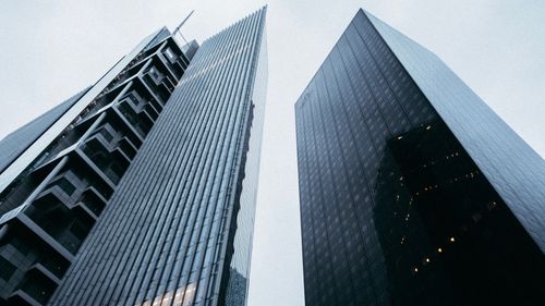Free Low-angle view of sleek skyscrapers with reflective glass facades under cloudy skies. Stock Photo