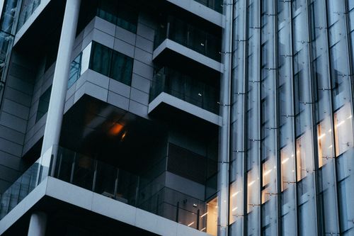 Free Low angle view of modern office building with glass facade and ambient lighting at dusk. Stock Photo