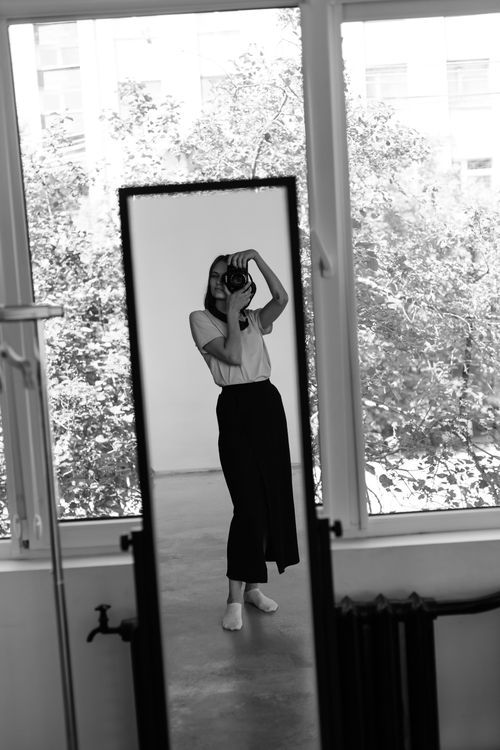 Free Monochrome image of a woman photographer reflecting in a mirror indoors. Stock Photo