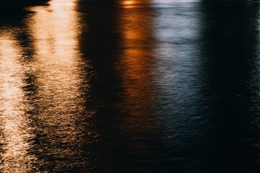 Moody abstract image showcasing colorful light reflections on a wet road surface at night.
