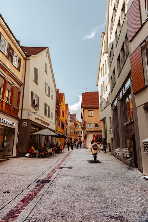 People Walking on an Alley Between Shops and Buildings