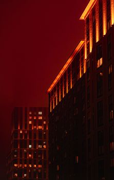 Red-lit skyscrapers against a dark night sky create a dramatic cityscape view.