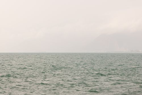 Free Serene ocean scene with misty mountains and a calm sea, perfect for peaceful settings. Stock Photo