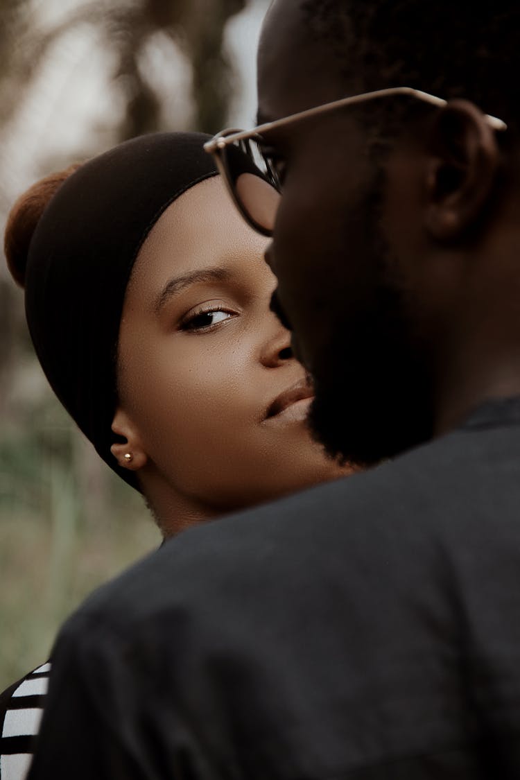 Woman Standing Behind A Man In Glasses And Looking Over His Shoulder