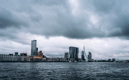 City Skyline Across Body of Water Under Cloudy Sky