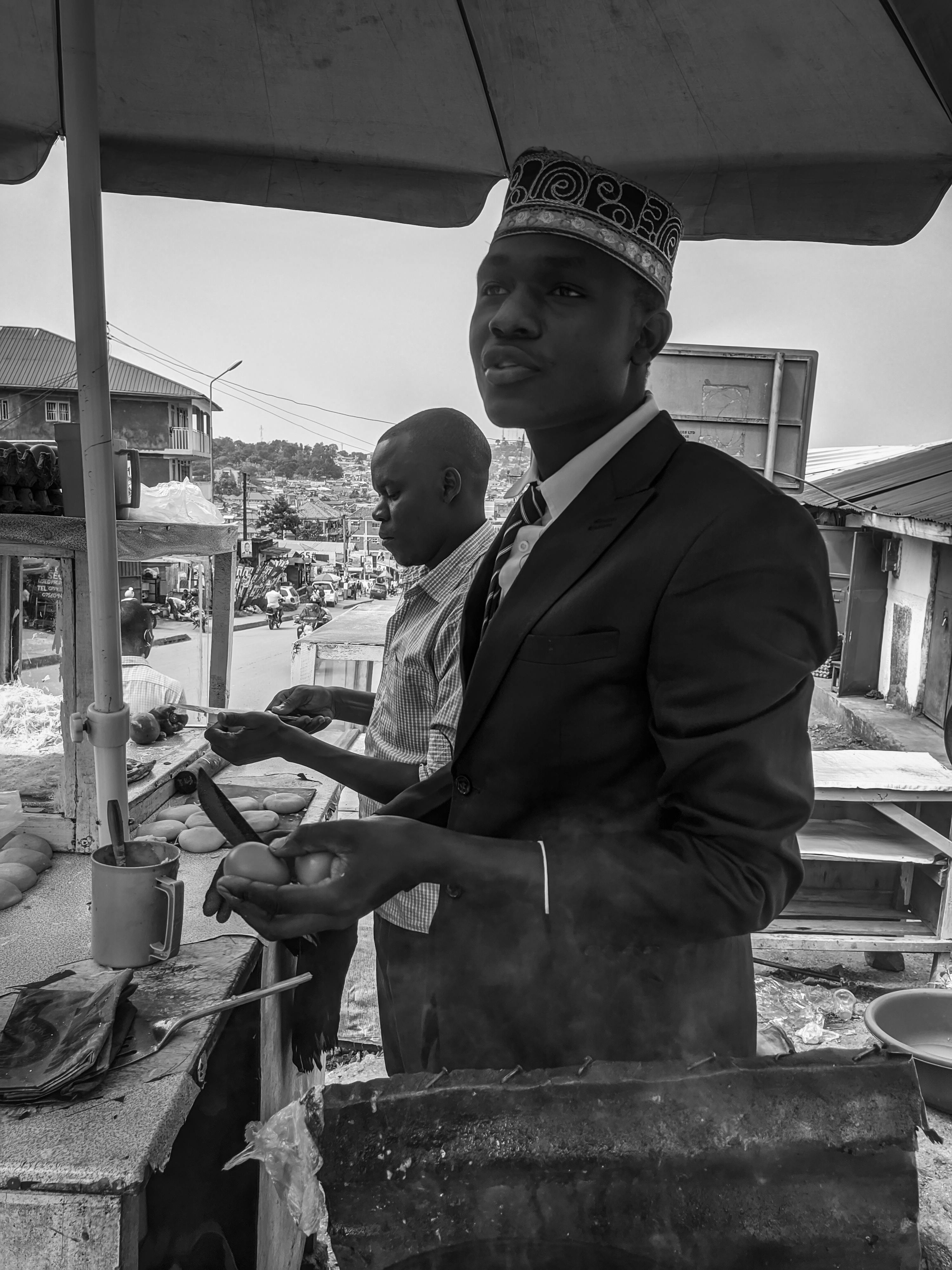 Black and white photo of a street vendor in Kampala making a traditional Ugandan rolex.