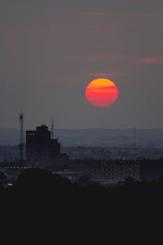 Capture of a vivid sunset over Aarhus, Denmark's urban skyline with silhouetted buildings and a striking orange sky.