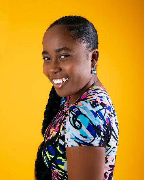 Free Portrait of a smiling woman with black hair in a colorful dress against a vibrant yellow background. Stock Photo