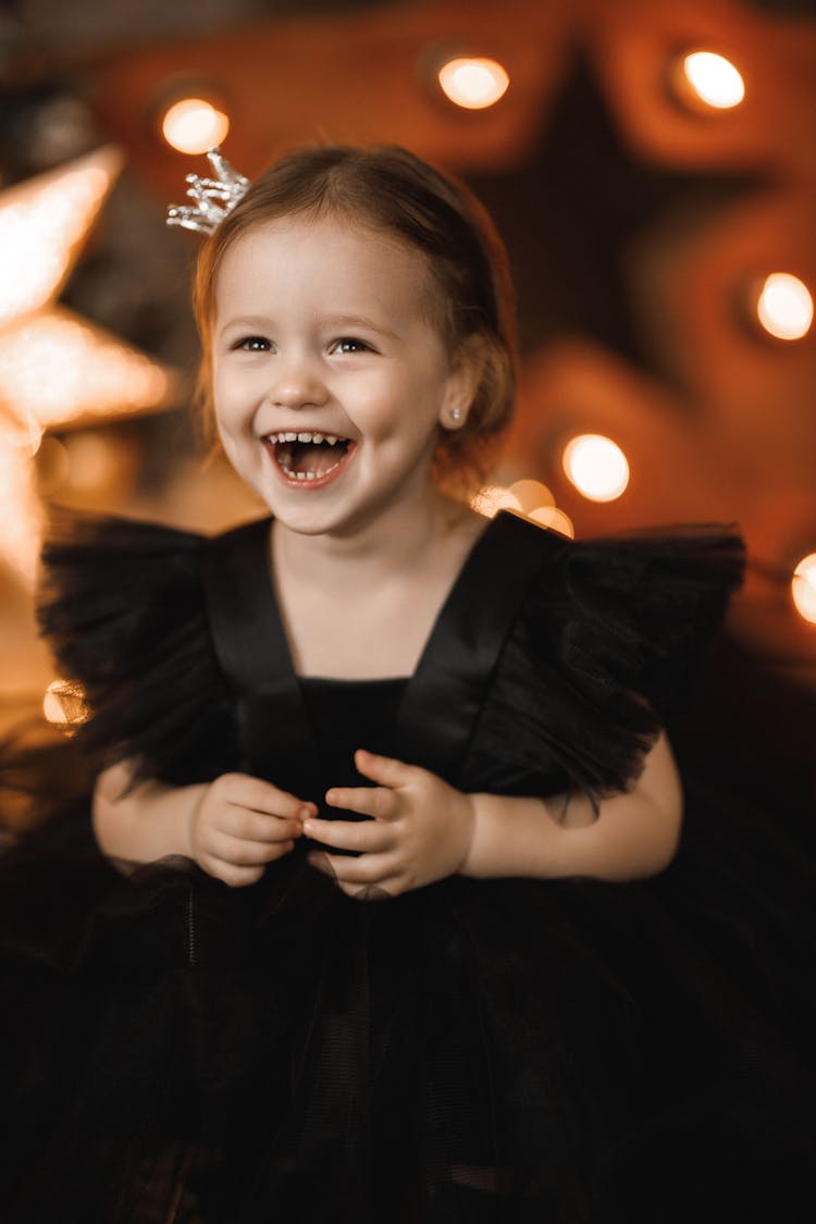 Portrait Of Laughing Girl Wearing Black Dress And Crown Hairpin