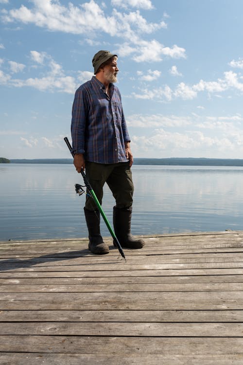 Elderly Man Standing on Pier with Fishing Rod