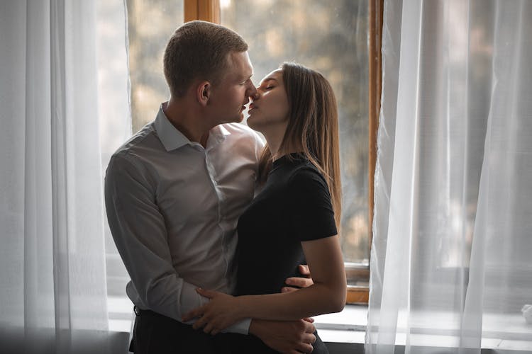 A Couple Kissing By The Window