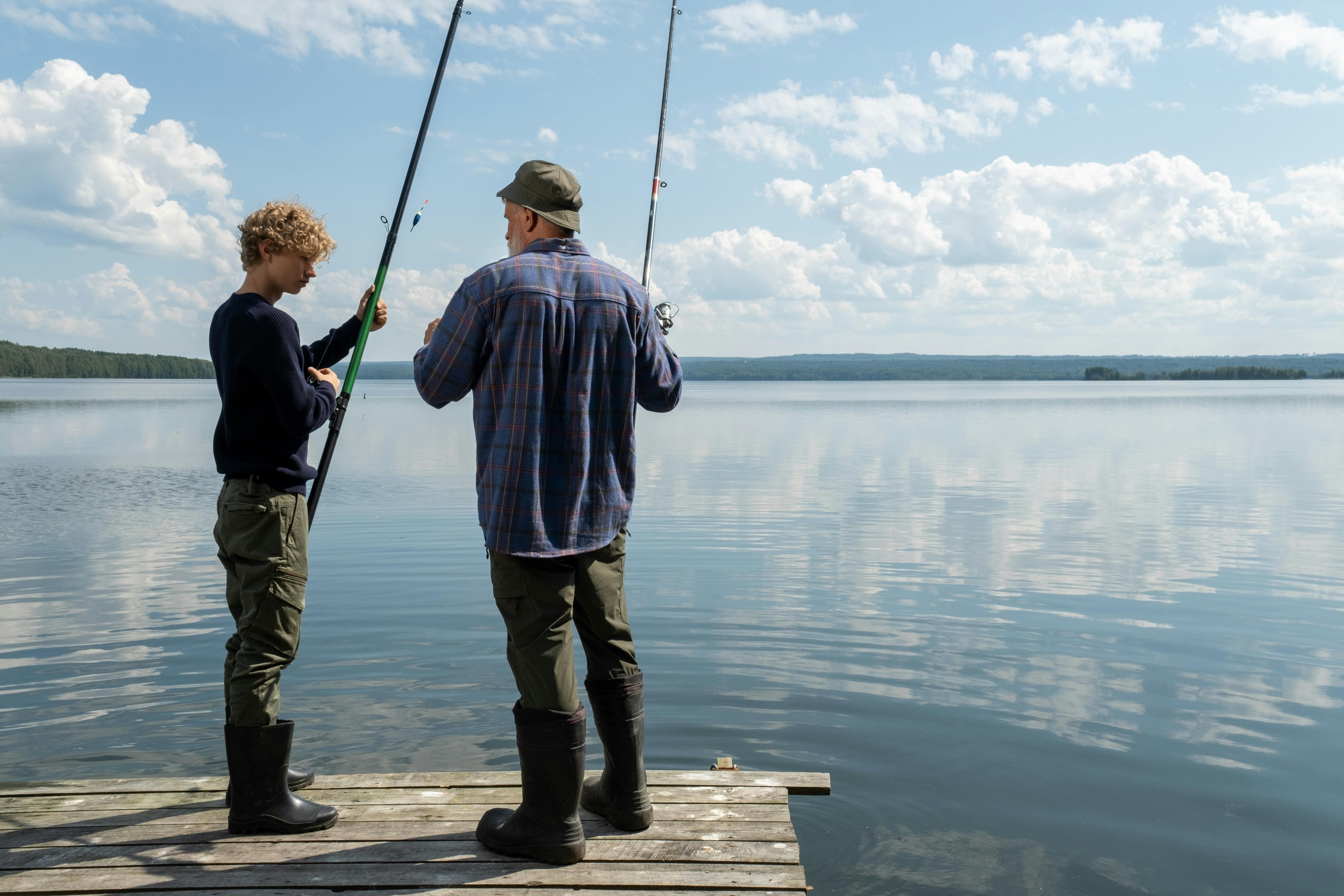 Teen Boy Standing On A Lake Dock With Fishing Rod High-Res
