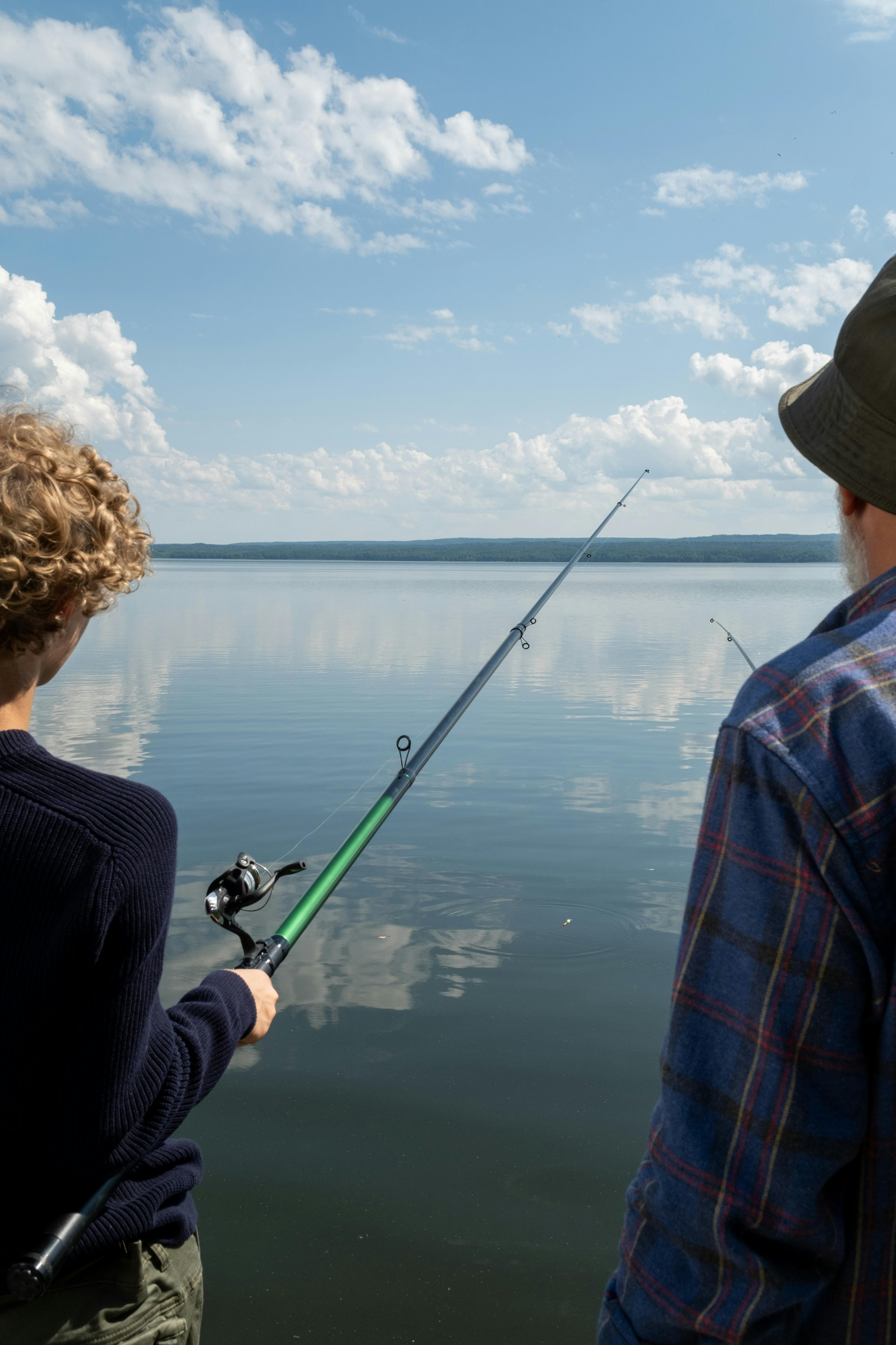 A Side View of Two Men Standing on a Wooden Dock while Holding a Fishing  Rods · Free Stock Photo