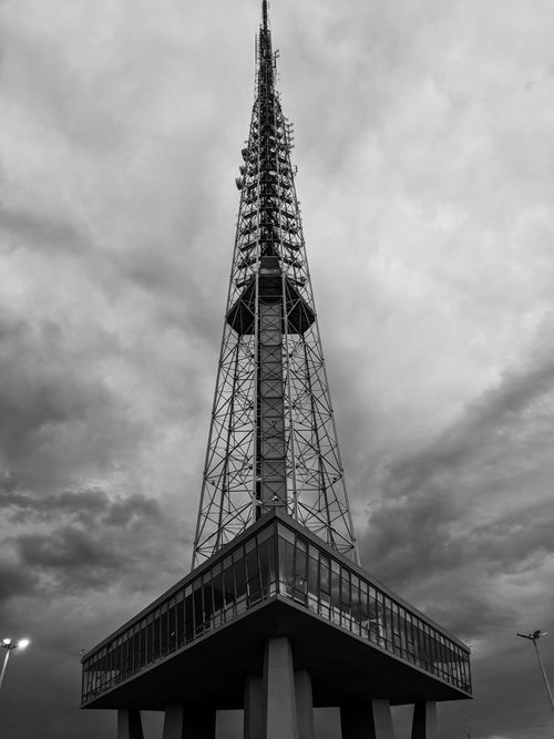 Free Monochrome image of a tower reaching into cloudy skies, emphasizing structure and mood. Stock Photo