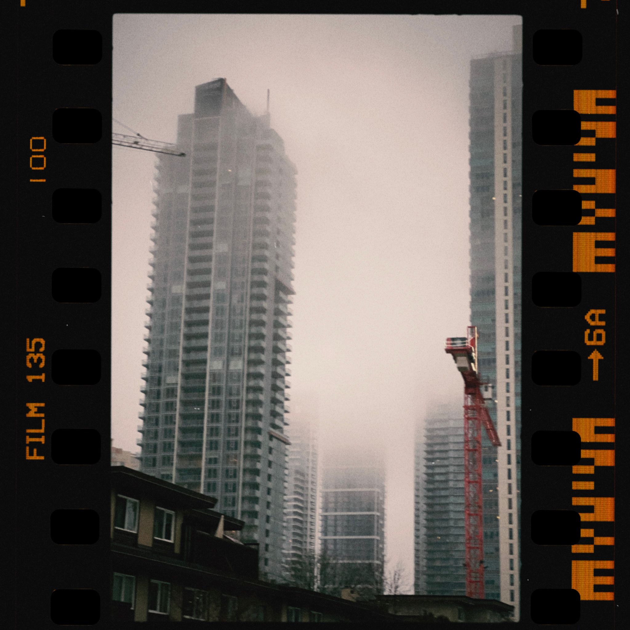 Misty urban cityscape featuring towering skyscrapers with a vintage film look.