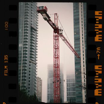 High rise buildings and a tower crane in a foggy cityscape.