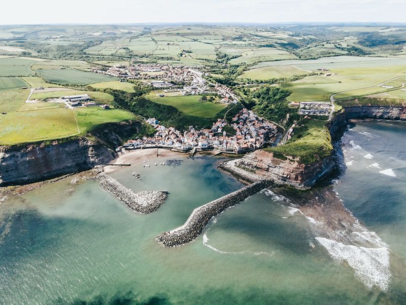 Aerial view of a coastal village below cliffs — photo by Lewis Ashton on Pexels