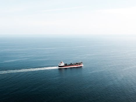 Aerial view of a cargo ship navigating through tranquil blue ocean waters.