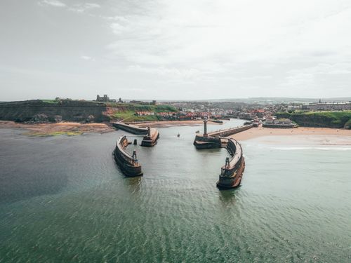 Free Drone shot capturing the scenic Whitby Harbour and surrounding coastline in North Yorkshire, England. Stock Photo